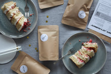 Lade das Bild in den Galerie-Viewer, Stück Beeren-Frischkäse-Torte auf Teller und Zutatenbeutel der Backbox